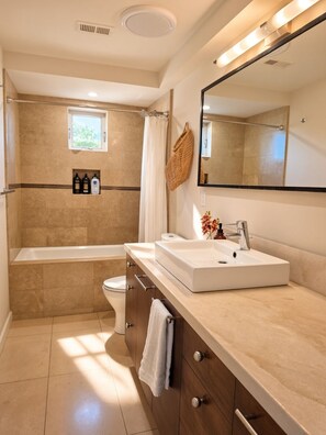 Een moderne badkamer met een badkuip, toilet, wastafel en een grote spiegel.