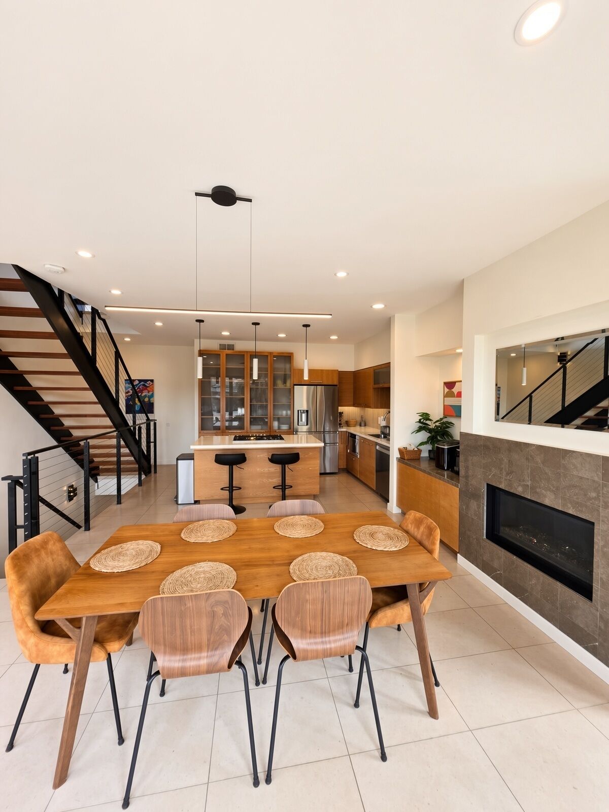 Een moderne keuken met een centraal eiland, ingebouwde apparatuur en een eetgedeelte met een houten tafel en stoelen.