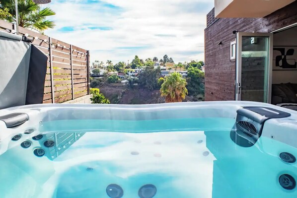 A hot tub with a view of a residential area and a modern building. - Hillside Oasis with Jacuzzi, Ocean Views, BBQ, Treetop Master, EV Charger (San Diego)