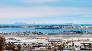 Un paysage urbain côtier avec un aéroport bien visible, comprenant des pistes et un avion stationné.