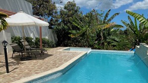 A swimming pool with a tiled edge, surrounded by lounge chairs and an umbrella. - Luxurious 6-bedroom villa with Pool, AC, WiFi, panoramic view in charming Rincon (Rincon)