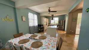 A dining area with a table set for four, a kitchen in the background, and a 'Welcome' sign on the wall. - Luxurious 6-bedroom villa with Pool, AC, WiFi, panoramic view in charming Rincon (Rincon)