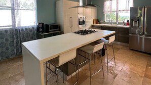 A modern kitchen with a central island, stainless steel appliances, and a ceiling fan. - Luxurious 6-bedroom villa with Pool, AC, WiFi, panoramic view in charming Rincon (Rincon)