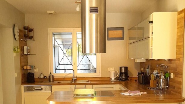 A modern kitchen with a central island, bar stools, stainless steel appliances, and a window with a view.