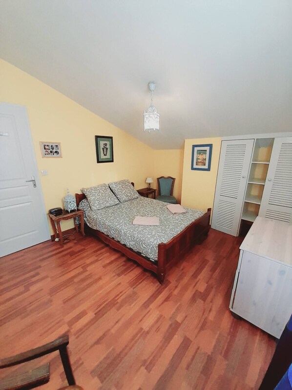 A bedroom with a bed, wooden floor, a desk, a chair, a wardrobe, and a chandelier. - Landes villa with swimming pool (Seignosse)