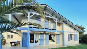 A two-story house with a balcony, a covered patio, and a well-maintained lawn.