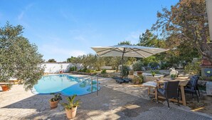 A swimming pool with a stone deck, surrounded by potted plants and outdoor furniture. - Gorgeous apartment in Jezera (Jezera)
