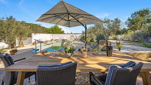 A wooden table with wicker chairs, a pool, and a pergola with a canopy. - Gorgeous apartment in Jezera (Jezera)