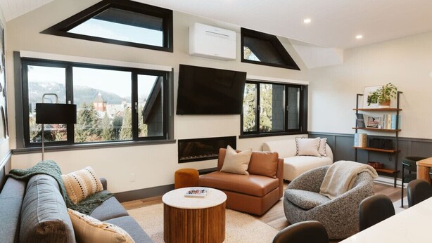 A modern living room with a fireplace, large windows, and a flat-screen TV.