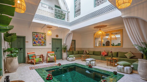 Un vaste espace intérieur doté d’une piscine centrale, de coins salon et d’éléments décoratifs.