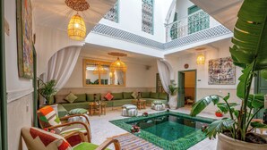 Un vaste espace intérieur comprenant une piscine, des sièges et des plantes décoratives.
