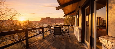 A wooden deck with a table and chairs, overlooking a mountainous landscape.