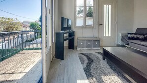 Een woonkamer met een bank, een televisie, een kast en een raam.