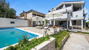 A modern villa with a swimming pool, outdoor seating, and a covered patio area. - Luxurious apartment in Vodice with house sea view (Vodice)