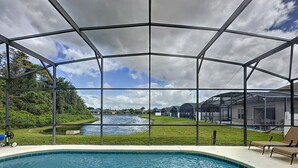 A swimming pool with a glass enclosure, a view of a river, and a grassy area with a chair. - Walk to Silver Spurs Rodeo and Heritage Park (Kissimmee)