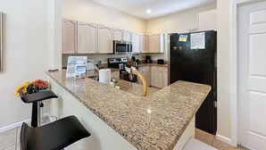 A modern kitchen with granite countertops, stainless steel appliances, and light wood cabinets. - Walk to Silver Spurs Rodeo and Heritage Park (Kissimmee)