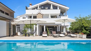 A two-story house with a swimming pool, outdoor seating, and a covered patio area.