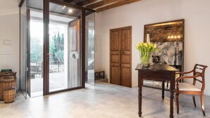 Una habitación con techo de madera, una puerta de vidrio que da al exterior, una mesa de comedor con sillas y un florero con flores.