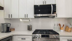 A modern kitchen with white cabinets, a stainless steel stove, an oven, a microwave, and a coffee maker. - Modern 3BR • 3.5 Bath • Near Downtown • Sleeps 10 (Houston)