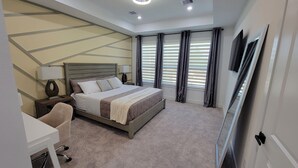 A modern bedroom with a large bed, a desk, and a chair. - Modern 3BR • 3.5 Bath • Near Downtown • Sleeps 10 (Houston)