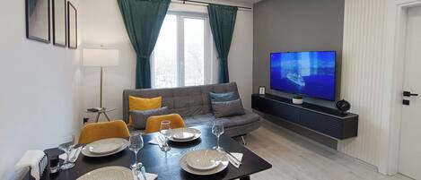 Cozy living area with a dining table for four, flat-screen TV, and comfortable sofa.