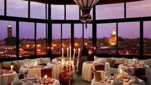 A restaurant with tables set for dining, featuring a cityscape view through large windows. - Charming  two-bedroom apartment in the centre of Marrakesh Gueliz (Marrakech)