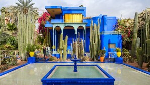 A blue building with a fountain in the center surrounded by cacti and other desert plants. - Charming  two-bedroom apartment in the centre of Marrakesh Gueliz (Marrakech)