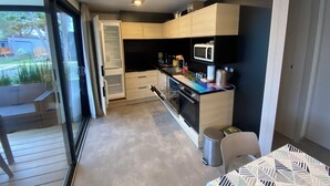 Une cuisine moderne équipée d’un four encastré, d’un micro-ondes et d’un petit coin repas agrémenté d’une nappe à motifs.