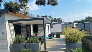 Une maison mobile moderne dotée d’un patio couvert, d’un espace salon extérieur et d’une allée en gravier.