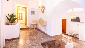 A well-lit hallway with a marble floor, a wooden bench, a small table with decorative items, and a wall-mounted light fixture. - Cozy apartment in Santa Margalida (Santa Margalida)