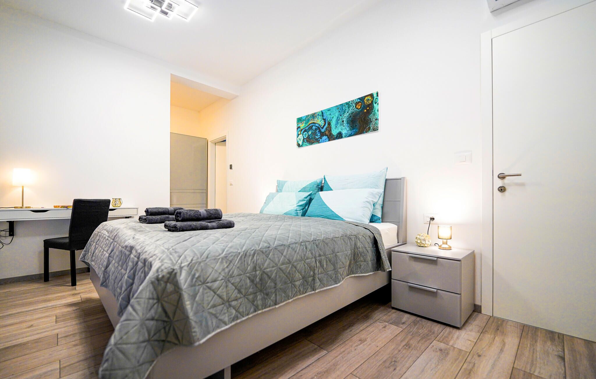 Une chambre bien rangée, avec un lit, un bureau et une table de chevet.