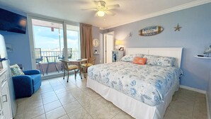 Un dormitorio con una cama grande, una silla, una mesita y un balcón con vistas.