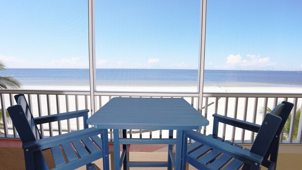 A balcony with a table and chairs overlooking a beach. - Casa Playa #402 Beach Front - Turtle's Nest (Fort Myers Beach)