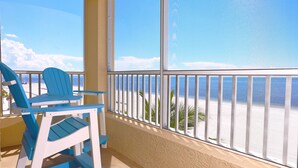 A balcony with a view of the beach, featuring two blue chairs and a white table. - Casa Playa #501 - One Bedroom Beach Front - Sand Dollar (Fort Myers Beach)