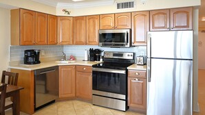 Una cocina con armarios de madera, un refrigerador de acero inoxidable, un microondas, un horno y un lavavajillas.