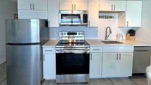 Una cocina moderna con electrodomésticos de acero inoxidable, armarios blancos y horno empotrado.