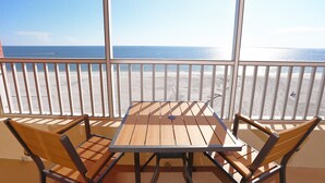 Un balcon avec une table et des chaises donnant sur une plage.