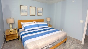 Une chambre à coucher avec un grand lit, deux tables de chevet et trois tableaux encadrés accrochés au mur.