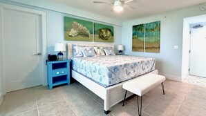 A bedroom with a bed, a nightstand, a bench, and artwork on the walls.