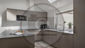 Eine moderne Küche mit eingebauter Mikrowelle, einer Kaffeemaschine und einem Fenster mit Jalousien.