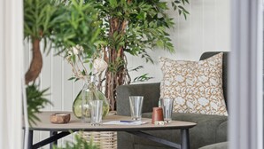 Ein gemütlicher Sitzbereich mit Tisch, Blumen in einer Vase und einer großen Pflanze.