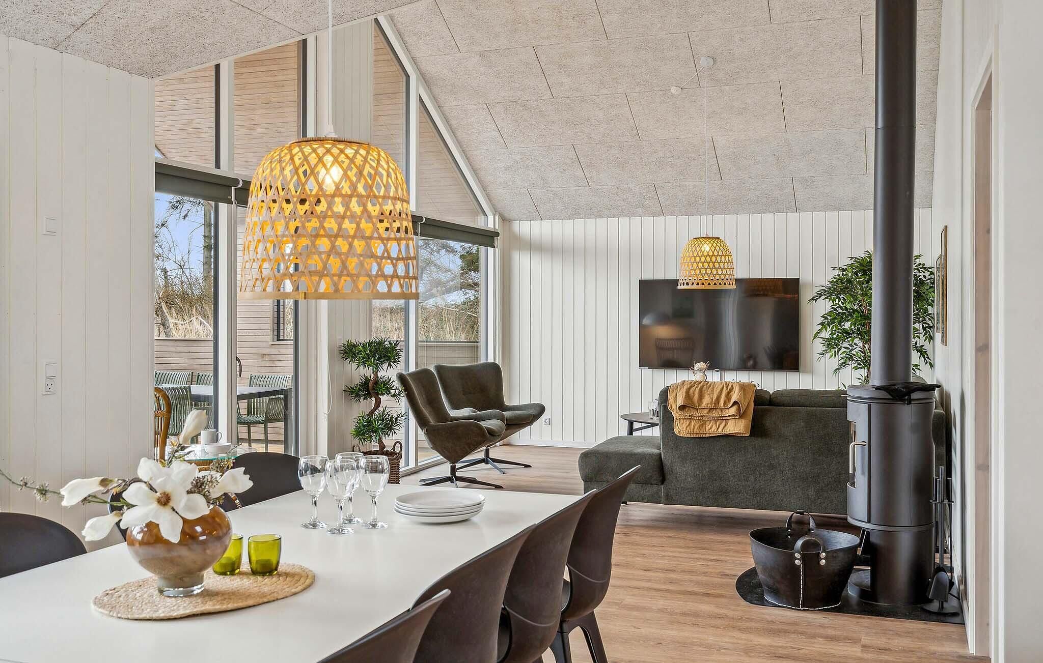 Un salon moderne comprenant un coin repas, de grandes fenêtres, un téléviseur à écran plat et une cheminée.