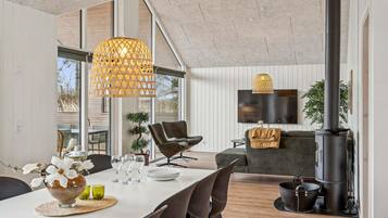 Un salon moderne comprenant un coin repas, de grandes fenêtres, un téléviseur à écran plat et une cheminée.