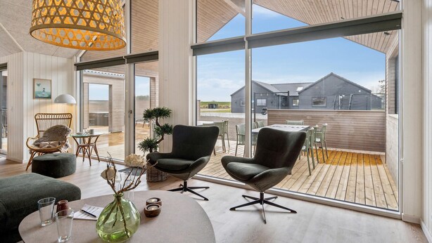 Ein modernes Interieur mit großem Fenster, einem Essbereich und Blick auf ein Gebäude.