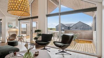 Un intérieur moderne avec une grande fenêtre, un coin repas et une vue sur un bâtiment à l’extérieur.