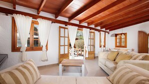A spacious living room with wooden beams, a sofa set, and a view of the outside. - Villa Alegre (Pollensa / Pollença)