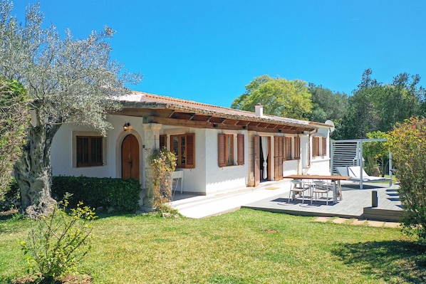 A two-story house with a tiled roof, a front porch, and a patio area with outdoor furniture.