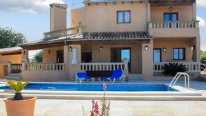 A two-story building with a swimming pool, outdoor seating, and a covered patio area.