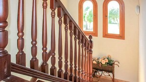 A wooden staircase with a handrail, leading to a landing area with a table and chairs.