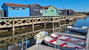 A row of colorful wooden buildings with a dock extending into calm water, where boats are moored. - 1 bedroom awesome home in Vaux-sur-Mer (Vaux-sur-Mer)